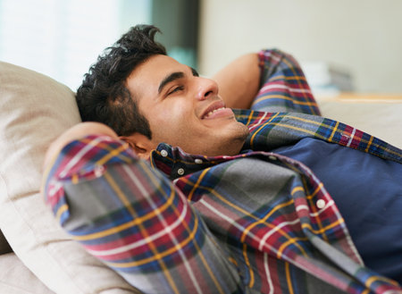 Comfortable contemplation. a handsome young man relaxing on the sofa at home.の写真素材