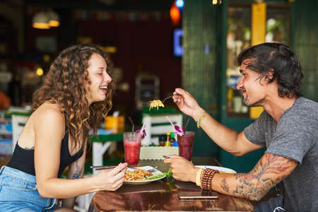 Try this, its delicious. two young tourists enjoying lunch together in a restaurant.の写真素材