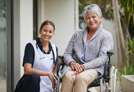 Her care and support makes the world of difference. Portrait of a senior woman in a wheelchair being for for by a nurse at a retirement home.の写真素材