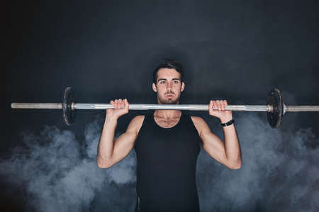 Unleash the beast. Studio shot of a young man working out with a barbell against a gray background.の写真素材