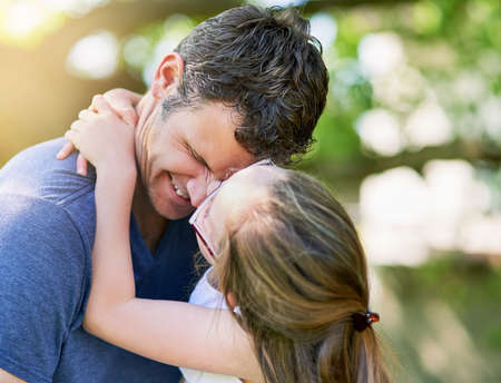 Love is such a wonderful feeling. a little girl giving her father a kiss outside.の写真素材