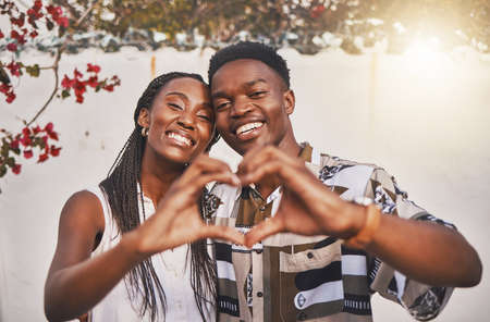 Happy couple heart love sign with their hands posing for a picture or photo while on vacation or holiday. Portrait of a loving and young African American lovers having fun together smiling in joyの写真素材