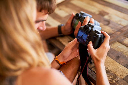 Comparing their photographic eyes. a young couple looking at pictures on their camera while on holiday in Thailand.の写真素材