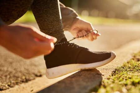 Nothing is going to trip her up today. an unidentifiable young woman tying her shoelace before going...