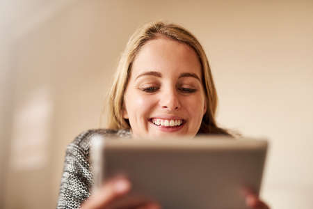 More and more people are following her blog each day. an attractive young woman using a digital tablet at home.の写真素材
