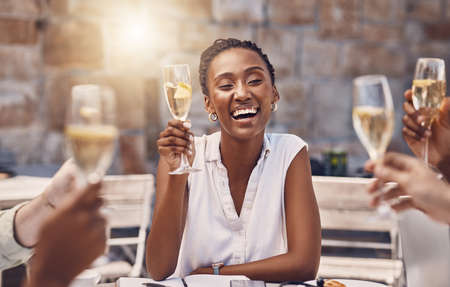 Woman talking for toast with celebration champagne at party with friends, wine for success at restaurant and drinks at social event. Happy black woman with smile and glass at birthday dinner at pubの写真素材