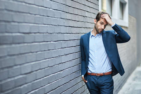 Hes got the look. a handsome young businessman standing against a grey facebrick wall.の写真素材