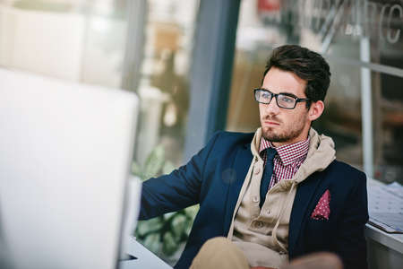 Putting his own spin on casual Friday. a trendy young businessman sitting with his feet on the desk...