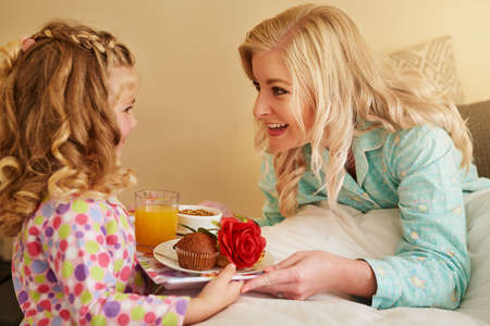 I can tell you made this with so much love. a little girl serving breakfast in bed to her mother at home.の写真素材