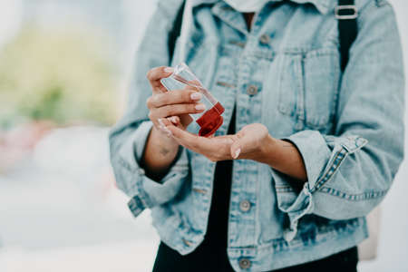 Closeup of woman using hand sanitizer while in public or travelling with copy space. Female practicing good health and hygiene, sticking to corona regulations. Lady suffering from OCD or germ phobiaの写真素材