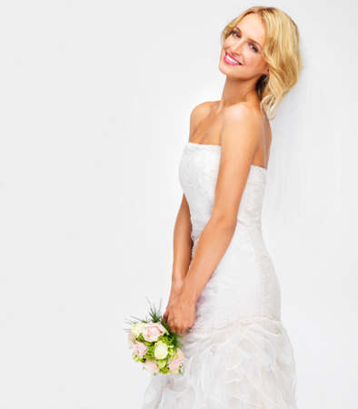 Portrait of bride wedding with flower bouquet and marriage dress on studio white background. Happy, smile and beauty of elegant young woman in bridal fashion getting married for celebration eventの写真素材