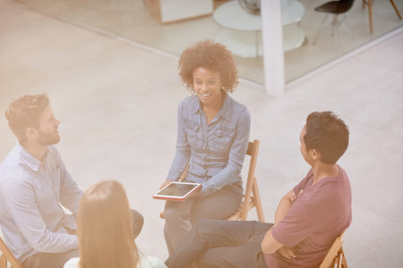Theyre innovating business. High angle shot of a group of businesspeople talking together while sitting in a circle in an office.の写真素材
