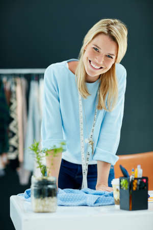 Im updating my designs to match the seasons latest styles. Portrait of a successful young fashion designer working in her studio.の写真素材