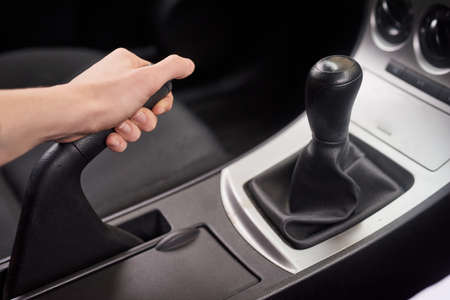 Locked into position. Closeup shot of a driver holding on to the handbrake lever of a motor vehicle.