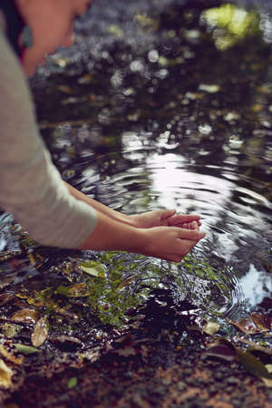 Water - with love from Mother Nature. a woman washing her hands in a pond.