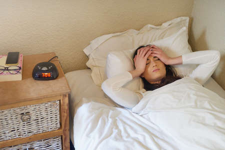 Why cant I just stay in bed today. a young woman waking up to her alarm in the morning.