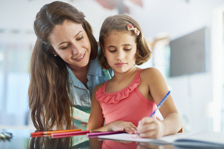 Watching her daughters creativity bloom. a mother watching her daughter colour in a picture.の写真素材