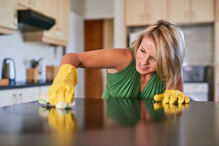 Getting rid of stubborn stains. a young woman cleaning a kitchen surface.の写真素材