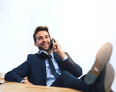 The perks of being the boss. a handsome young businessman using a cellphone with his feet up on the desk.の写真素材