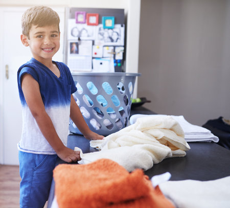 Laundry challenge Mission completed. Portrait of a little boy folding towels at home.の写真素材