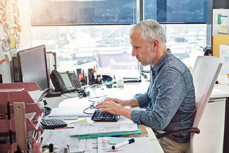 He knows his stuff. a mature man at work on computer in an office.