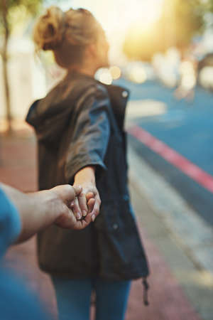 Shes a big city lover. a young woman pulling on her boyfriends hand.の写真素材