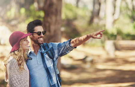 Take a look over there. an affectionate young couple during a hike.の写真素材