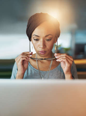 Meeting deadlines is what she does. a young woman using her laptop while working late in her office.