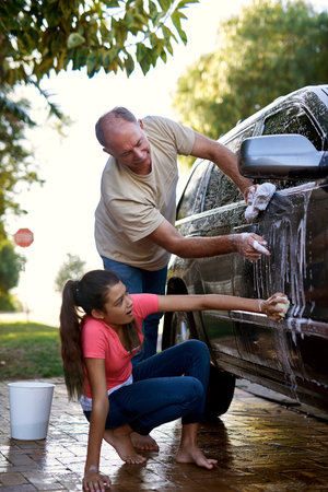 Making sure they dont miss a speck of dirt. a father and daughter washing a car together outside.の写真素材