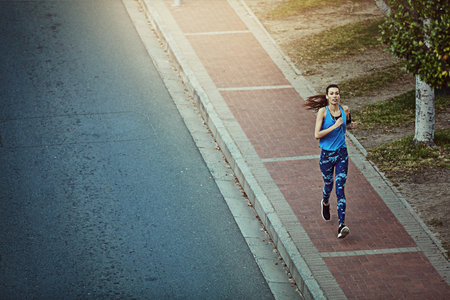 Running towards a healthier me. a young woman out in the city for her morning run.