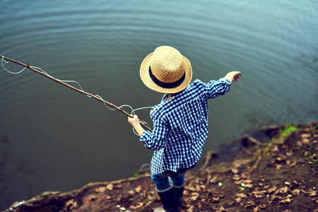 I think I got something. Rearview shot of a little boy fishing in the forest.の写真素材