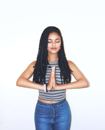 Studio shot of an attractive young woman standing in a meditation-like position.