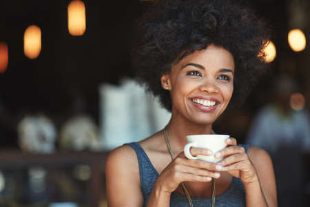 Coffee is a great way to start the day. a young woman enjoying a beverage at a cafe.の写真素材