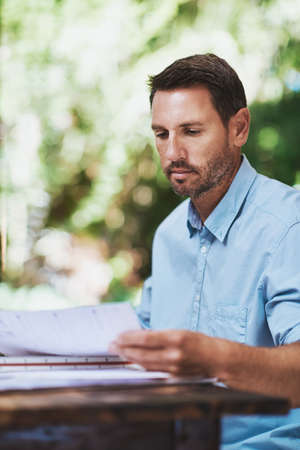 Hes all about the details. a businessman reading some paperwork at home.