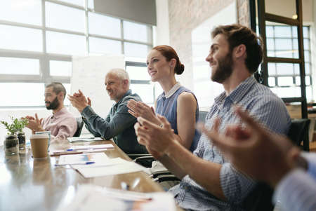 That deserves a round of applause. a group of businesspeople applauding during a meeting in the...