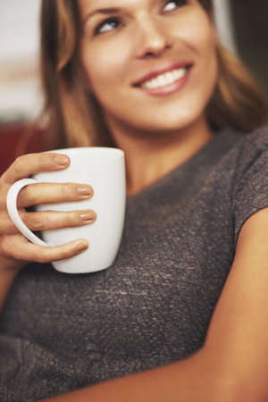 Relaxing at home, now thats my cup of tea. a young woman enjoying a warm beverage at home.の写真素材