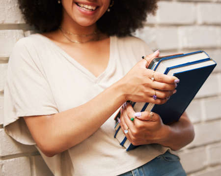 Happy student with books on university campus, scholarship for education at school and smile for learning at library. African girl studying law, doing research and motivation for future careerの写真素材