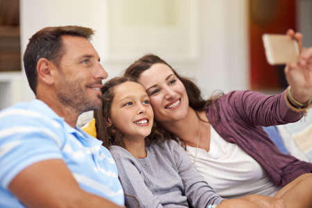 Selfie smiles. a family sitting on the sofa at home.の写真素材