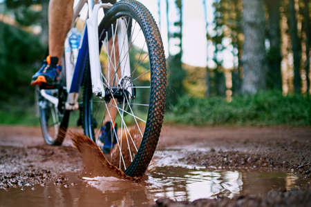 Getting dirty is part of the fun. a male cyclist riding along a muddy mountain bike trail.