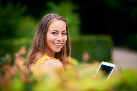 My favorite spot for some leisurely browsing. a young woman using a digital tablet at the park.