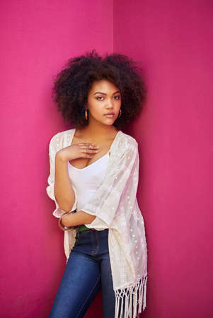 Shes got her own style. Portrait of an attractive young woman posing against a pink background.