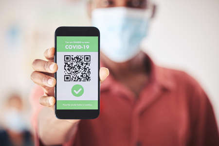 Covid, QR code and phone in person hand for vaccinated digital verification certificate or passport at an airport, hospital or clinic. Man with smartphone and screen technology for coronavirus safetyの写真素材