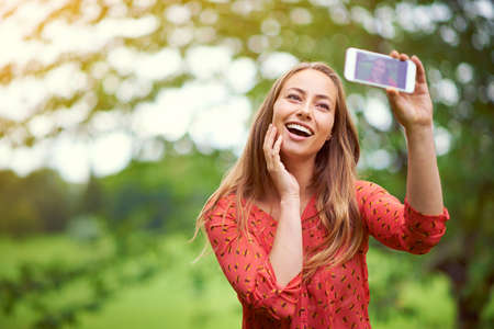 Sunshine and happiness selfie. a young woman taking a selfie outside.の写真素材