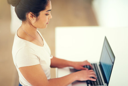 Shell put in the hours required to be successful. a young businesswoman working on her laptop at home.の写真素材