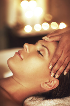Let relaxation take over. Closeup shot of a young woman enjoying a head massage at the spa.の写真素材