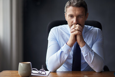 Letting the pressure get to him. a mature businessman looking anxious while working in his office.の写真素材