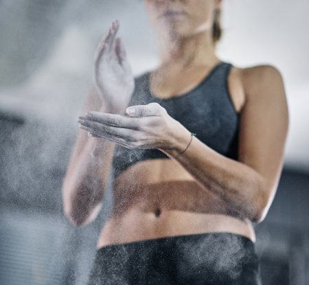 Success starts with discipline. a female athlete coating her hands with sports chalk.の写真素材