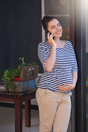 Its nearly time for my maternity leave. a young pregnant woman using her cellphone while standing in...