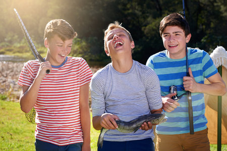 Theres something fishy going on here...three young boys laughing while standing with the fish they...