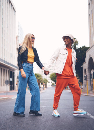 Happy interracial couple with fashion clothing in a urban city street with a smile and love. Trendy, stylish or punk man and woman walking in a town road with funky, edgy and style togetherの写真素材